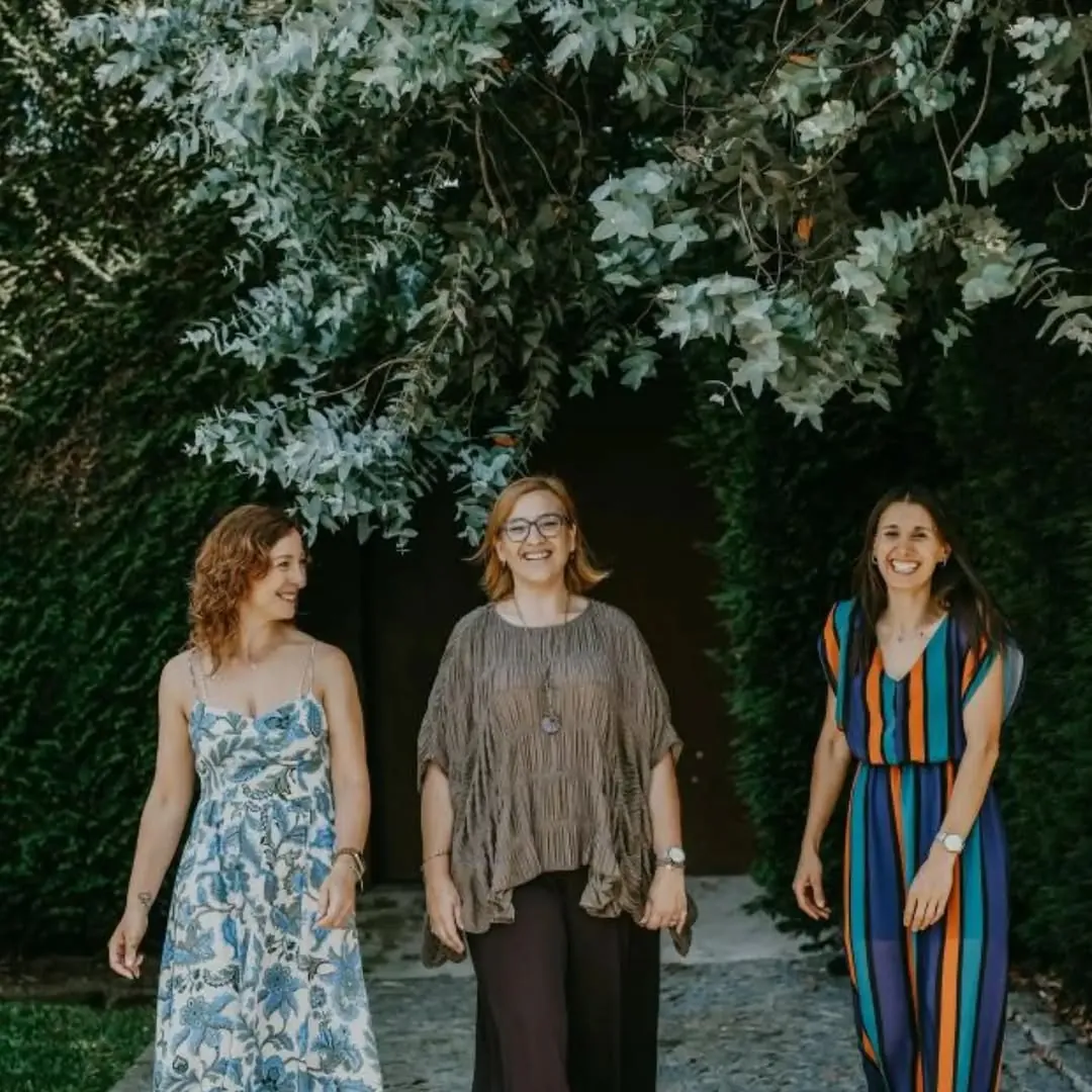As três celebrantes a sorrir num jardim, sob a folhagem